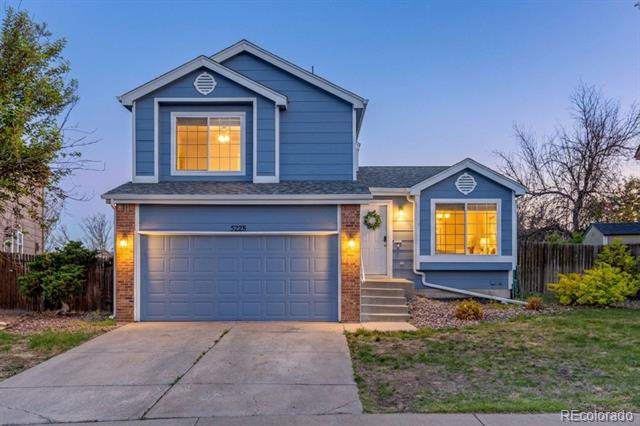 Blue two-story house at dusk with a double garage and warmly lit windows.