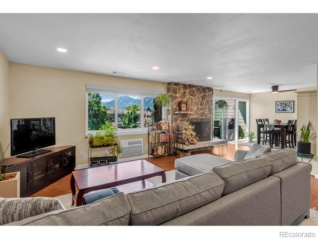 Furnished living room with a stone fireplace and mountain views through large windows.