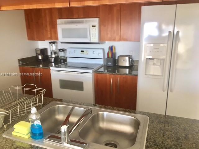 Kitchen with reddish wood cabinets, granite counters, and a stainless-steel double sink.