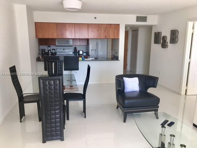 Open-plan condo living and dining area with black furniture, glass table, and kitchen bar.