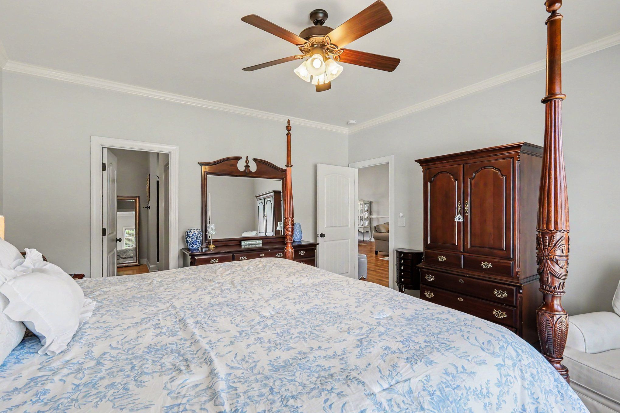 Furnished bedroom with a four-poster bed, blue floral bedding, and dark wood furniture.