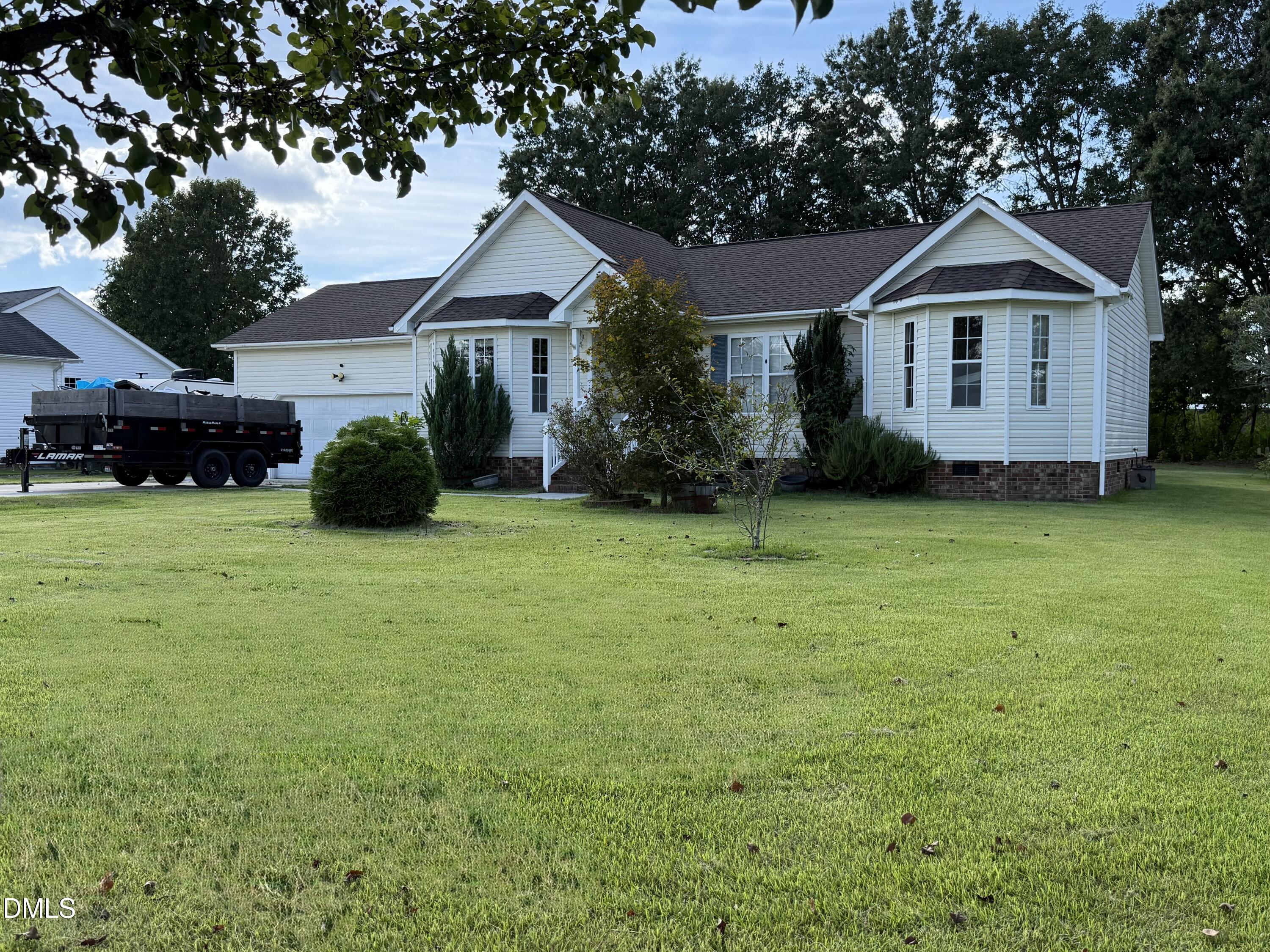 White-sided home with multiple gables, an attached garage, and a broad green lawn.