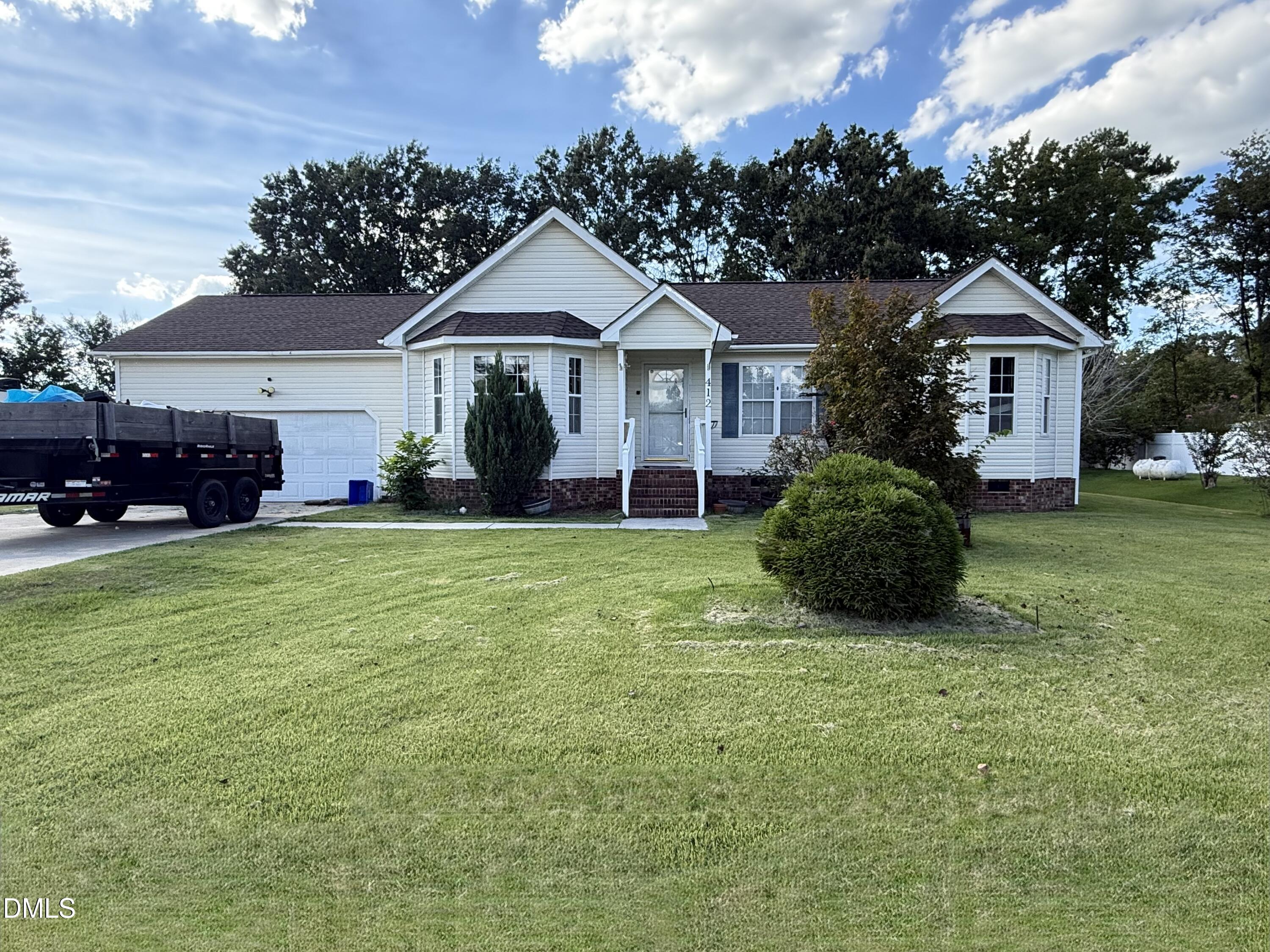White single-story house with an attached garage, bay windows, and a broad front lawn.