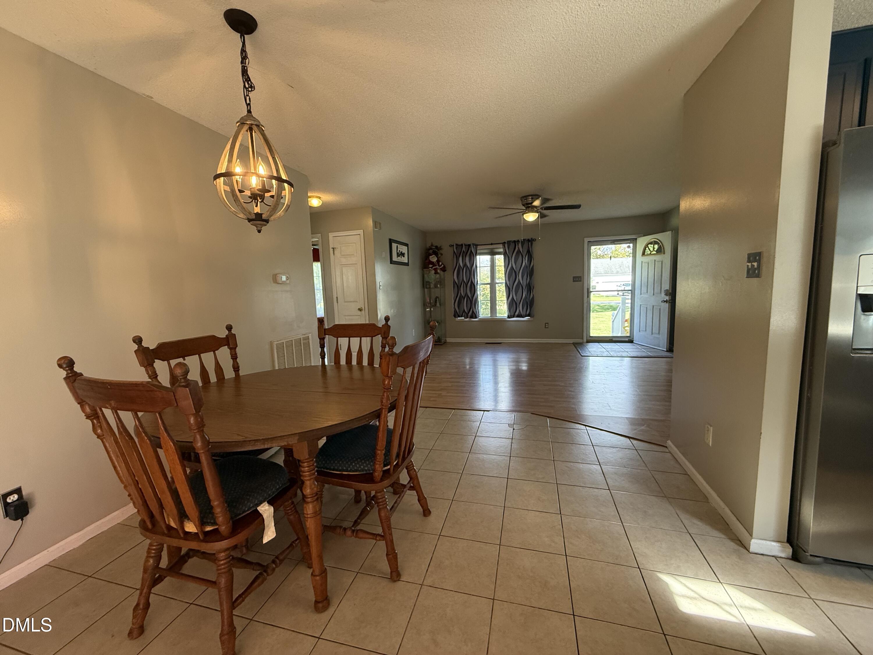 Dining area with wooden table and chairs opens into a living room with wood floors and a ceiling fan.