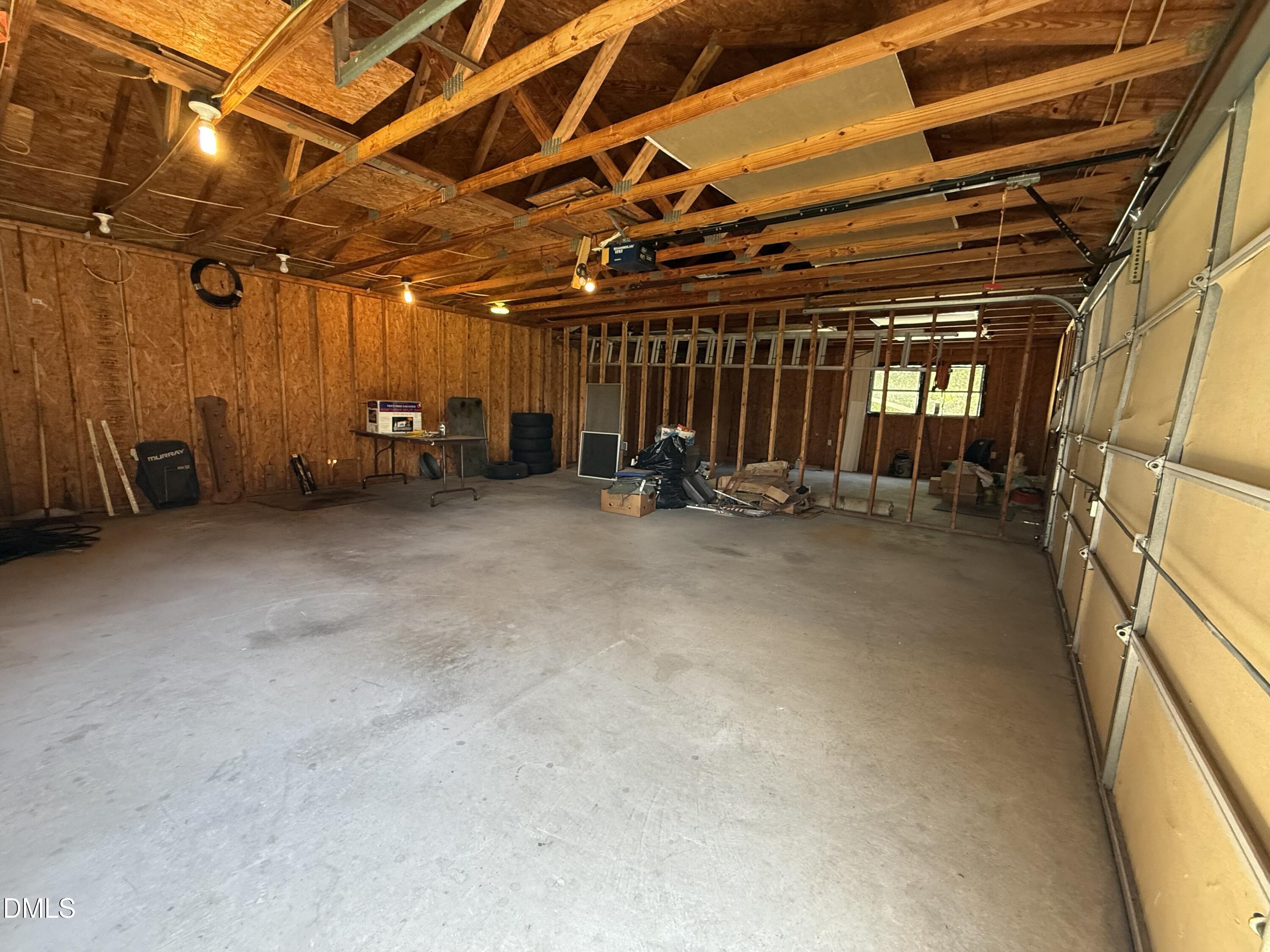 Unfinished garage with exposed wood framing, concrete floor, and a closed overhead door.