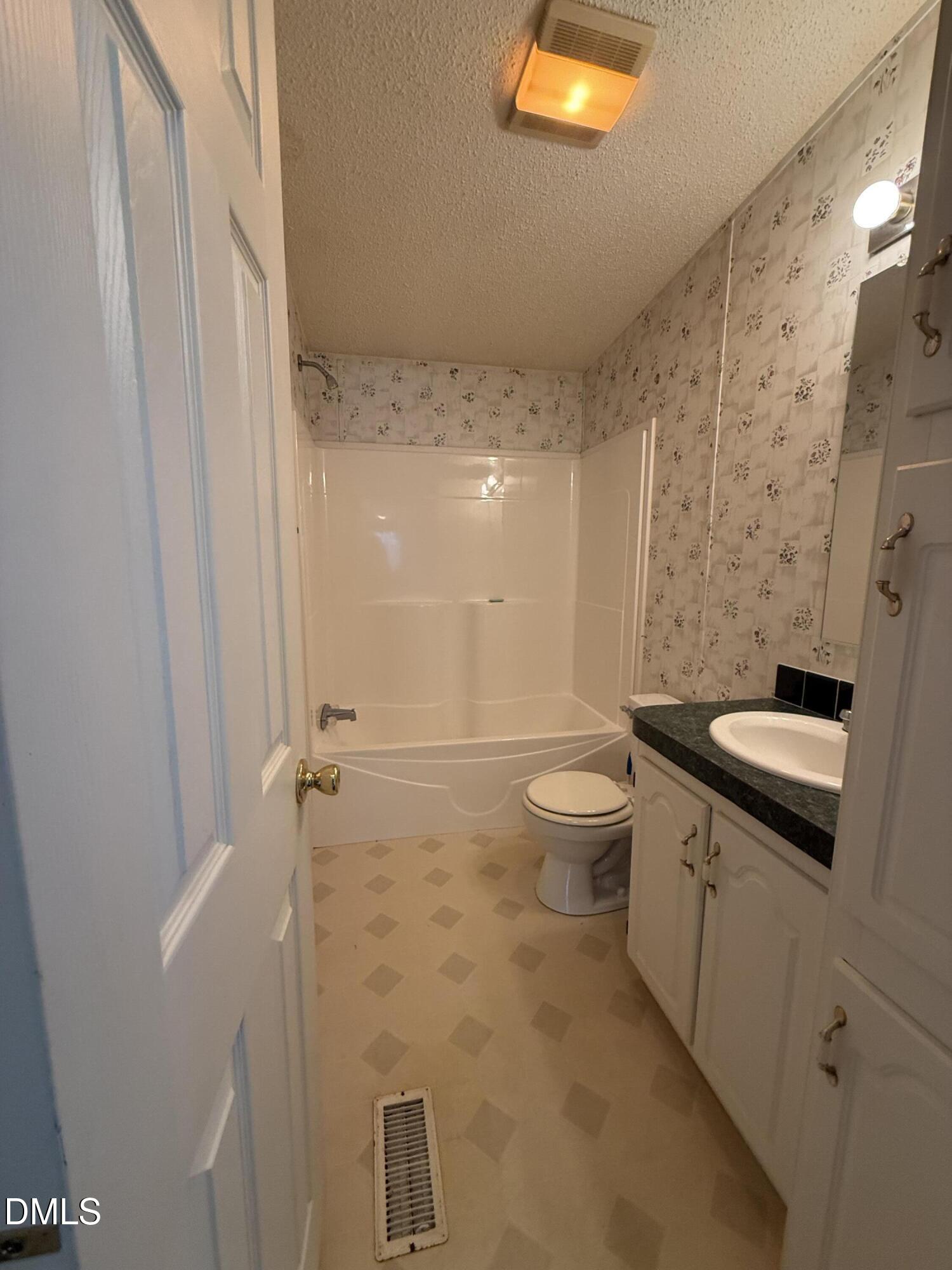 Bathroom with tub and shower, toilet, and dark-countertop vanity.