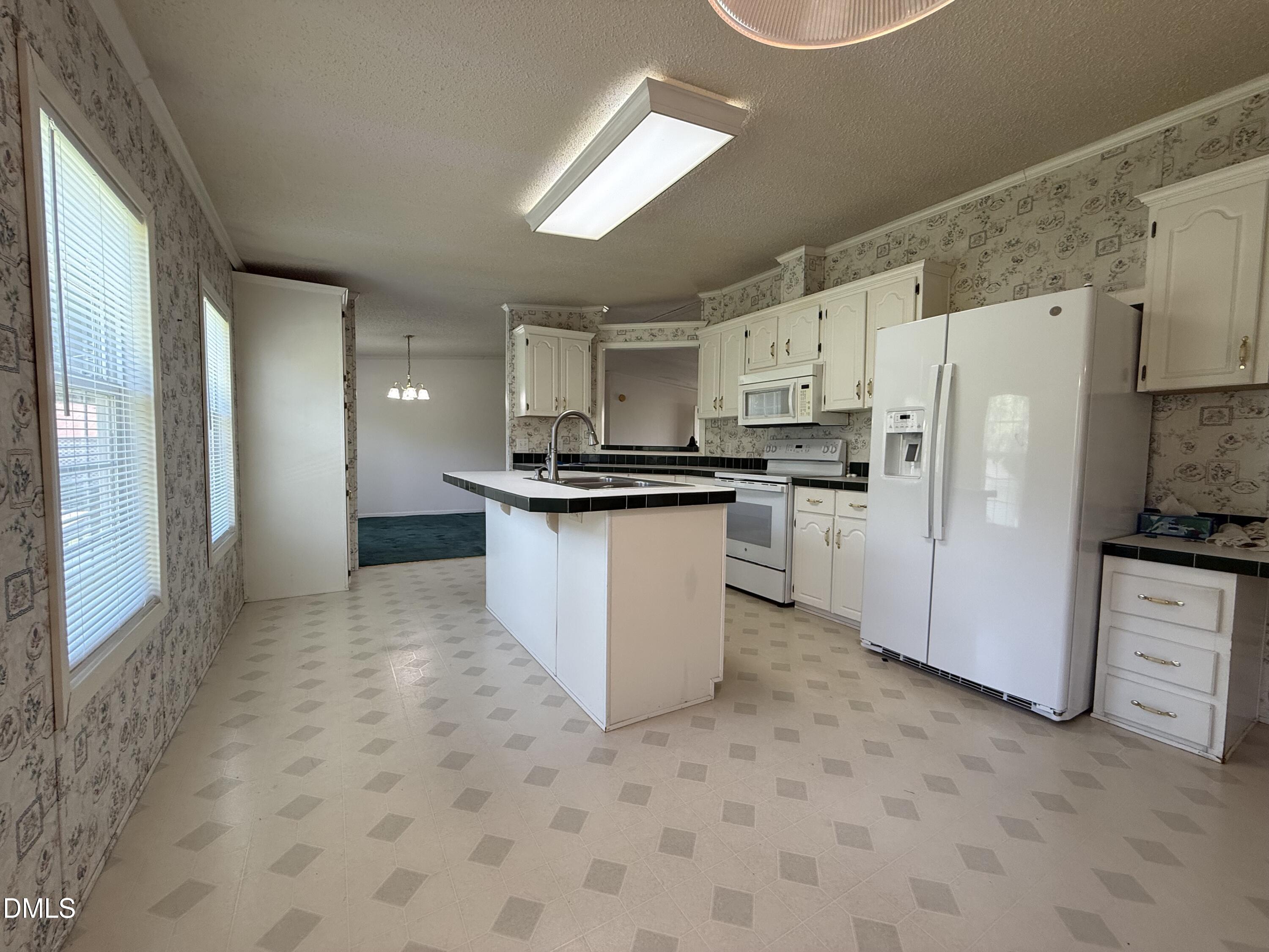 Kitchen with a central island, white cabinetry, and a large side-by-side refrigerator.