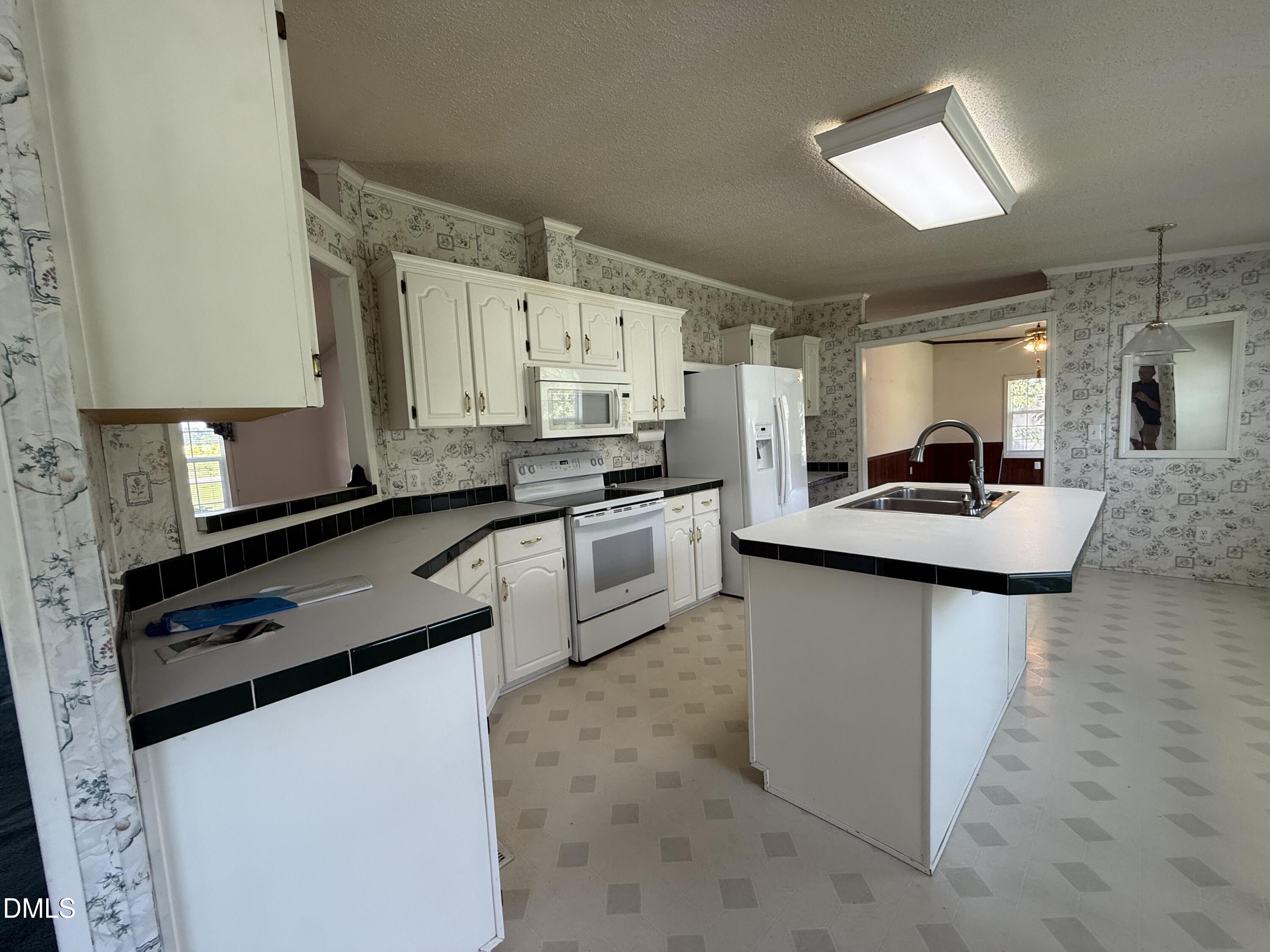 Kitchen with white cabinets, black-edged counters, and a large island with a double sink.