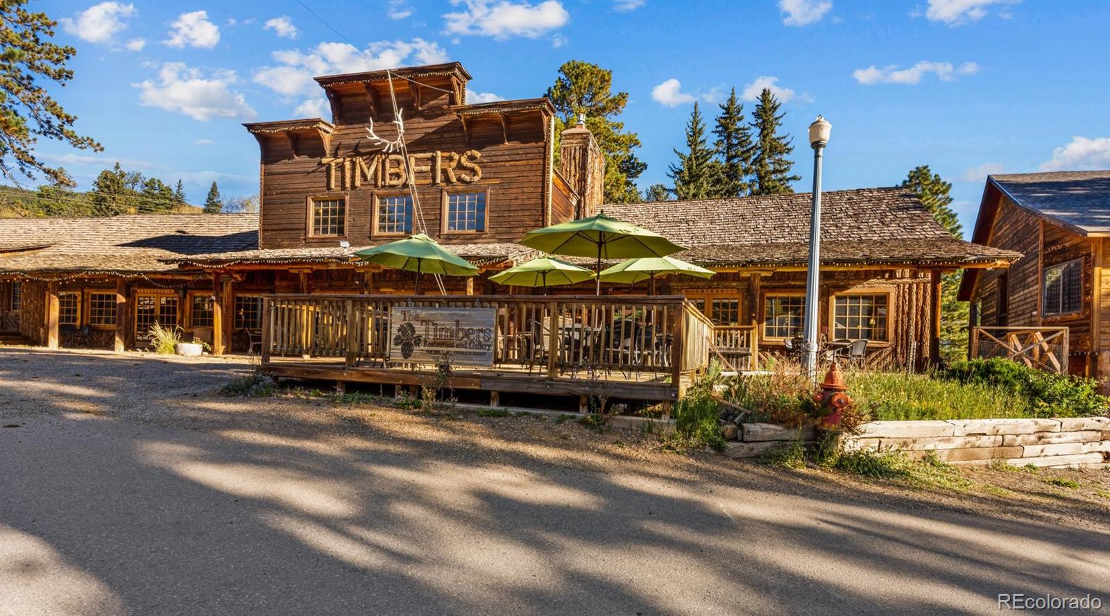 Rustic timber restaurant exterior with a raised patio and green umbrellas.