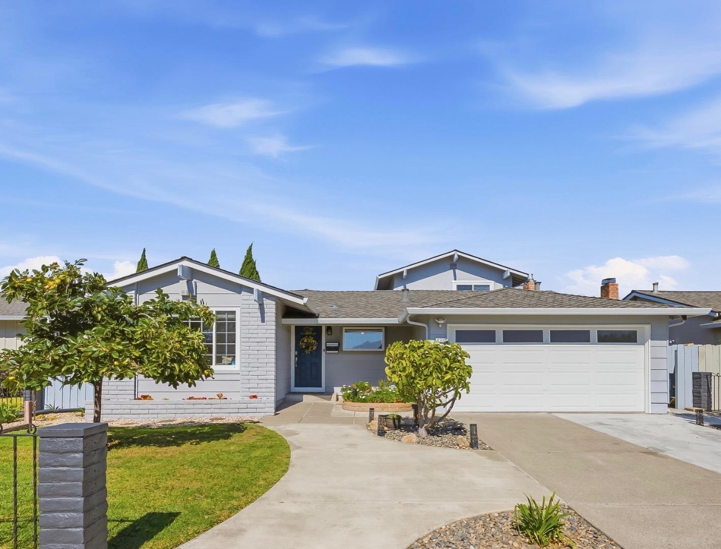 Gray single-story home with a blue front door, white garage, and landscaped yard.