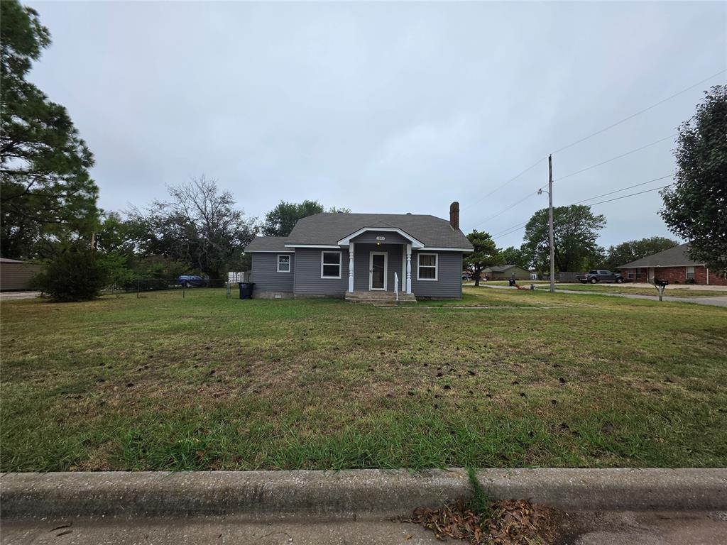 Gray single-story house with a covered porch and broad front lawn.