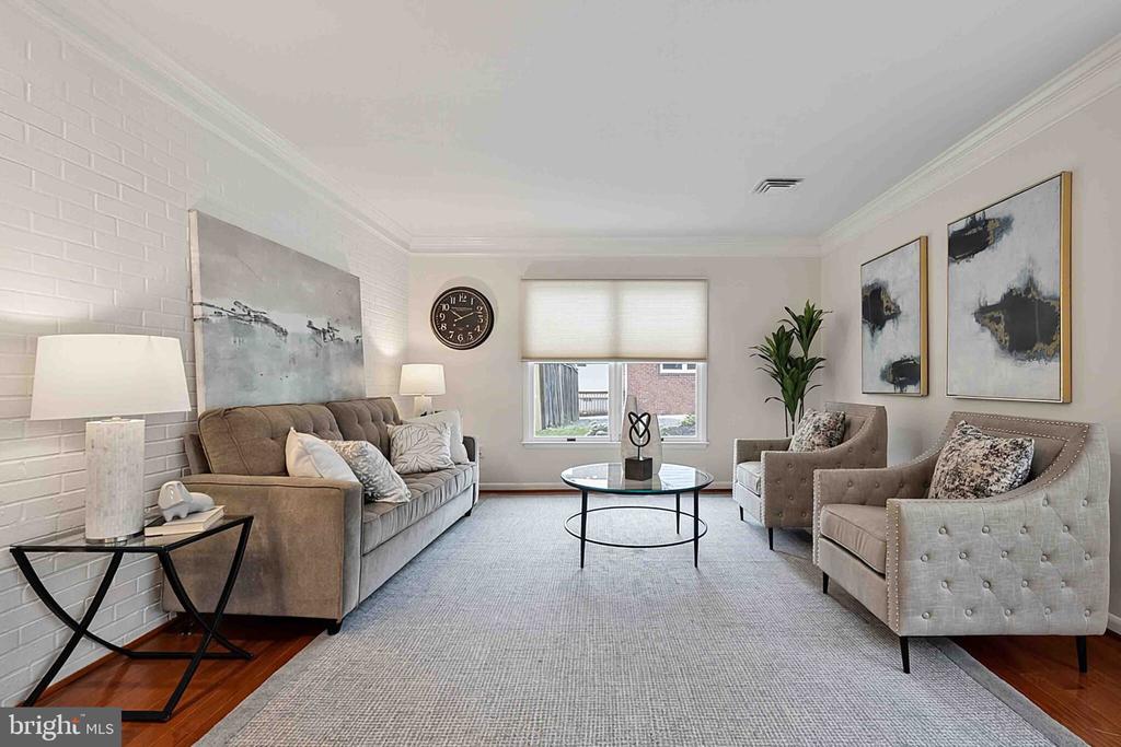 Staged living room with a white brick accent wall, taupe seating, and abstract art.