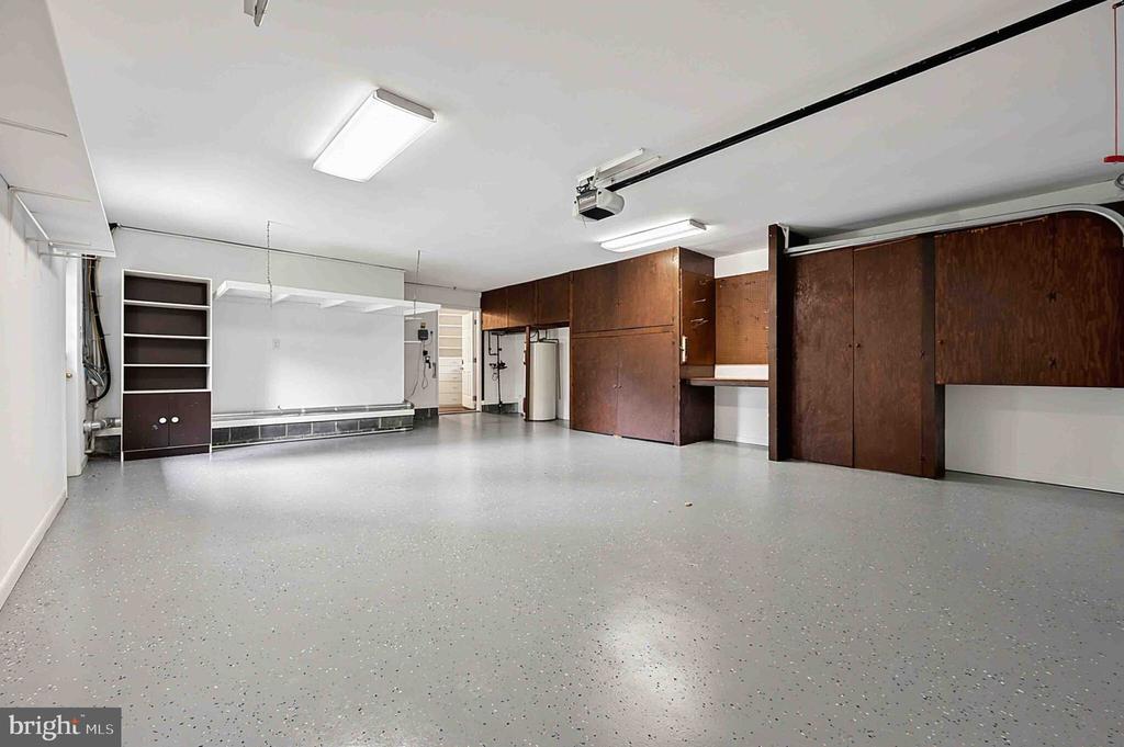 Garage with dark built-in cabinets and shelving over a speckled gray floor.