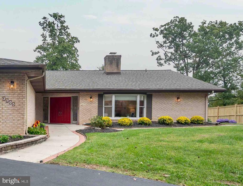 Single-story brick home with a red front door, curved walkway, and landscaped lawn.