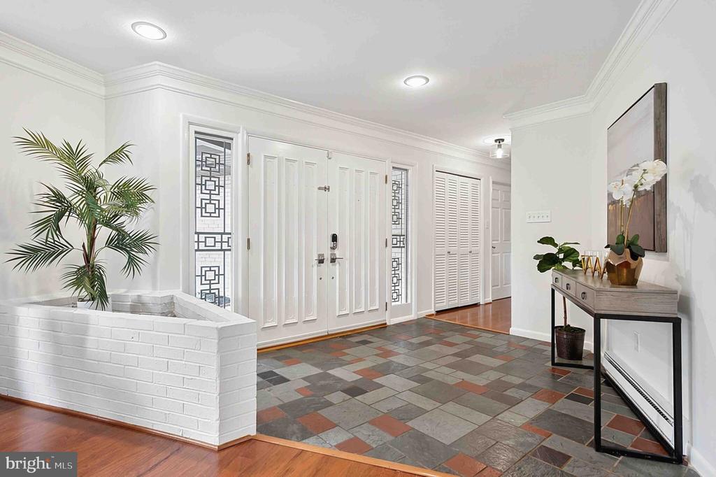 Entry foyer with a paneled white front door, patterned slate floor, and built-in planter.