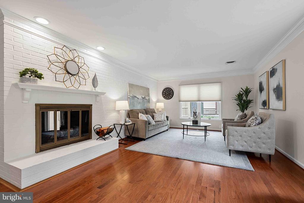 Staged living room with white brick fireplace, hardwood floors, and gray seating.