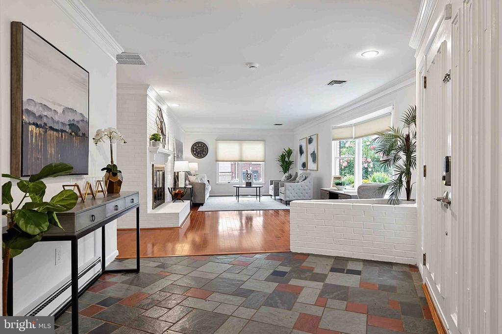 Foyer opening to a living room with a white brick fireplace and slate tile floor.