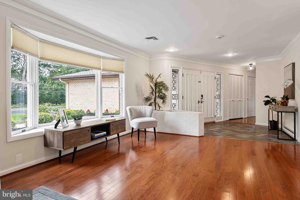 Furnished foyer with hardwood floors, a white entry door, and large windows overlooking the yard.