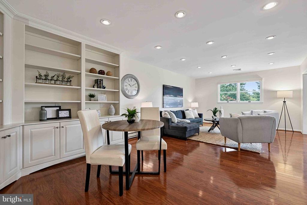 Living room with white built-ins, dark sofas, a gray armchair, and a dining nook.