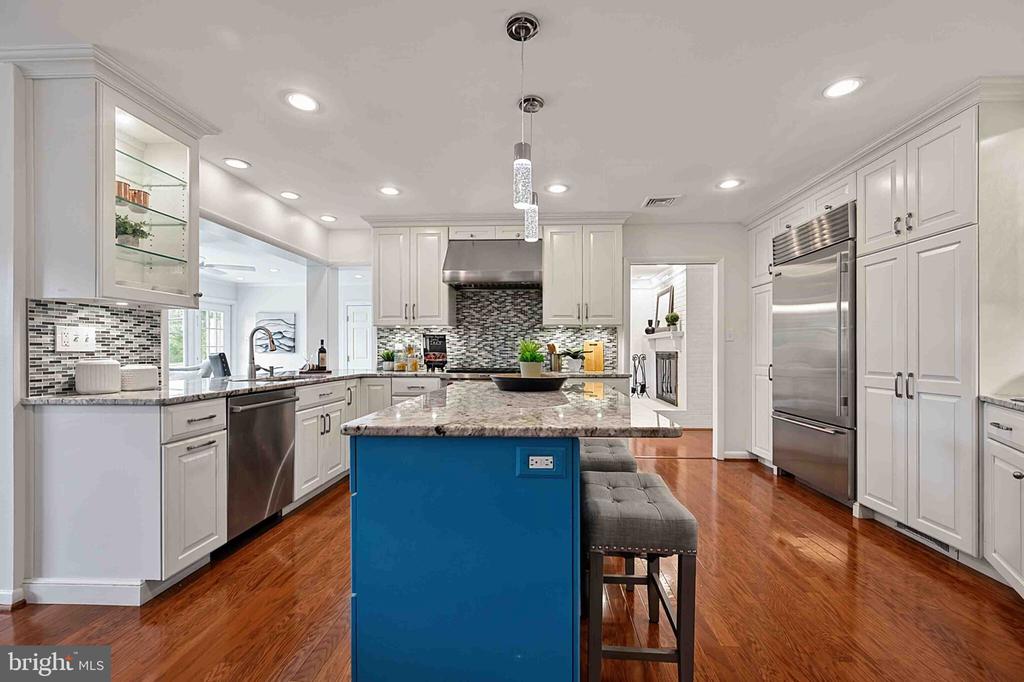 Kitchen with white cabinets, stainless steel appliances, and a blue island topped with stone.