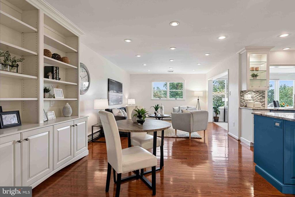 Open-plan dining and living area with built-in shelving, hardwood floors, and a blue kitchen island.