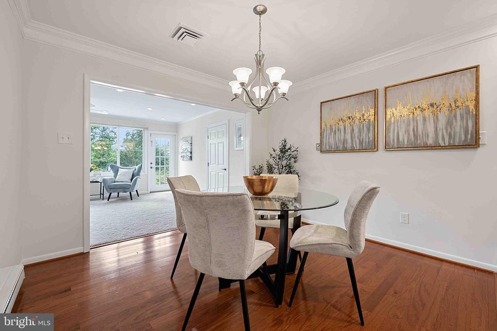 Dining room with a glass-top table and upholstered chairs, open to a bright sitting area.