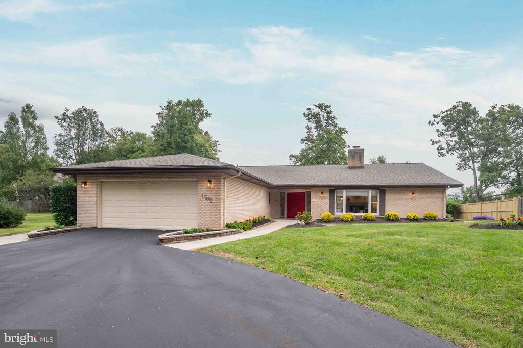 Single-story brick home with a red front door, attached garage, and broad driveway.