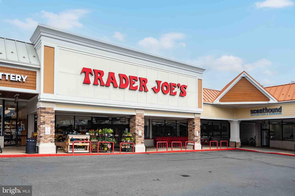Trader Joe’s storefront in a shopping center, with Scenthound next door and red cart rails.