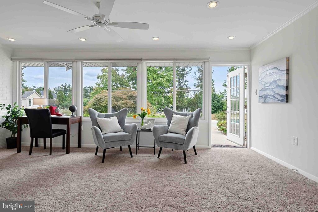 Sitting room with gray armchairs and broad windows opening to a patio.