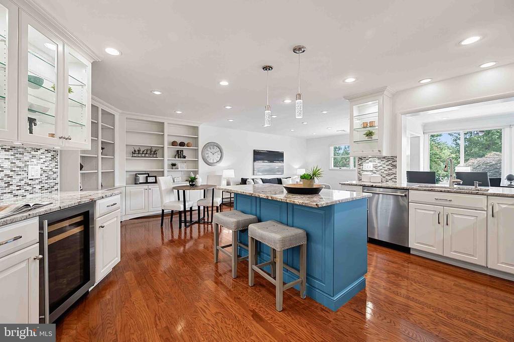 Open-plan kitchen with a blue island, white cabinetry, and hardwood floors.