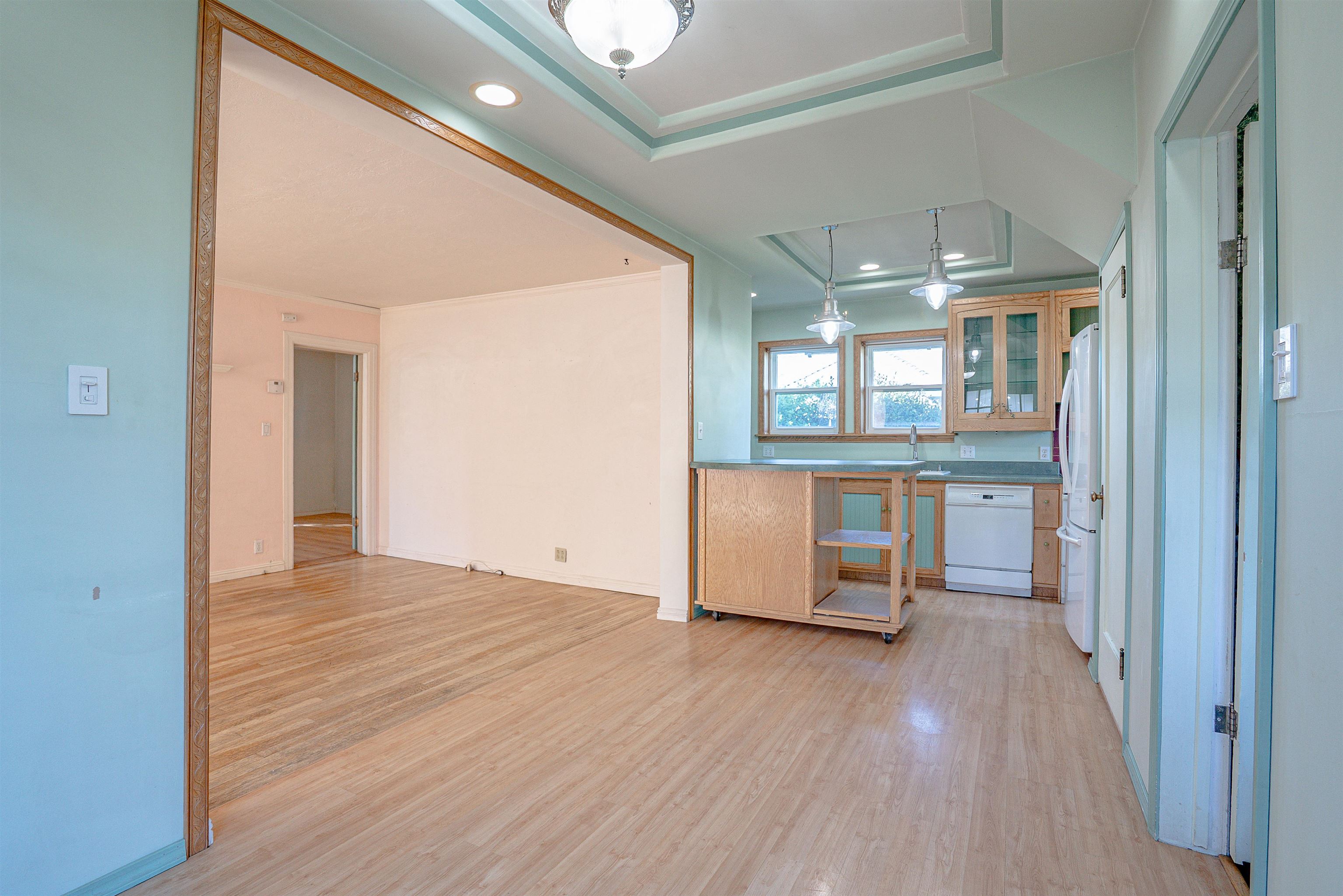 Kitchen and adjoining dining area with wood cabinets, an island, and light wood flooring.