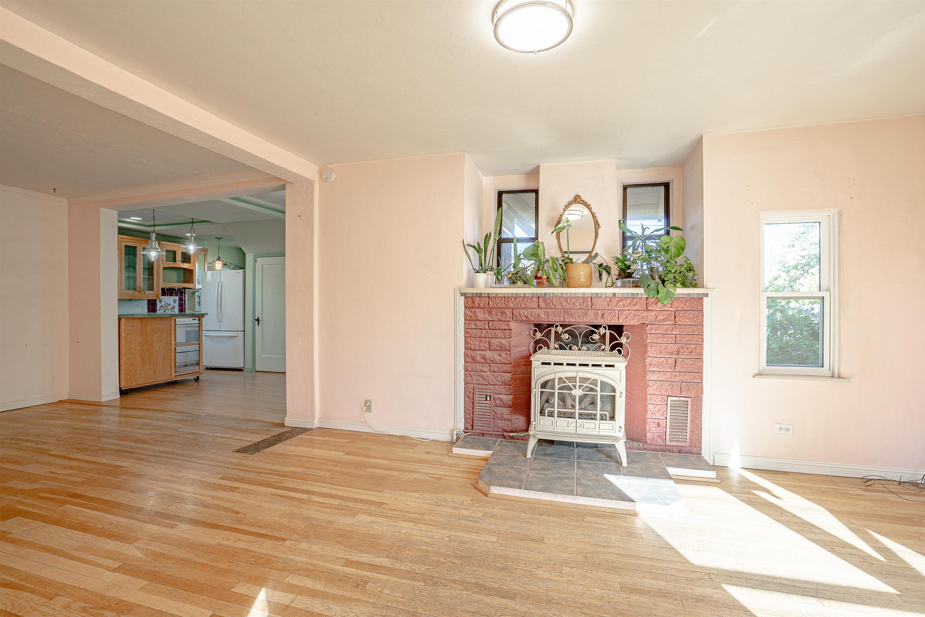 Living room with a red brick fireplace, freestanding stove, and view into the kitchen