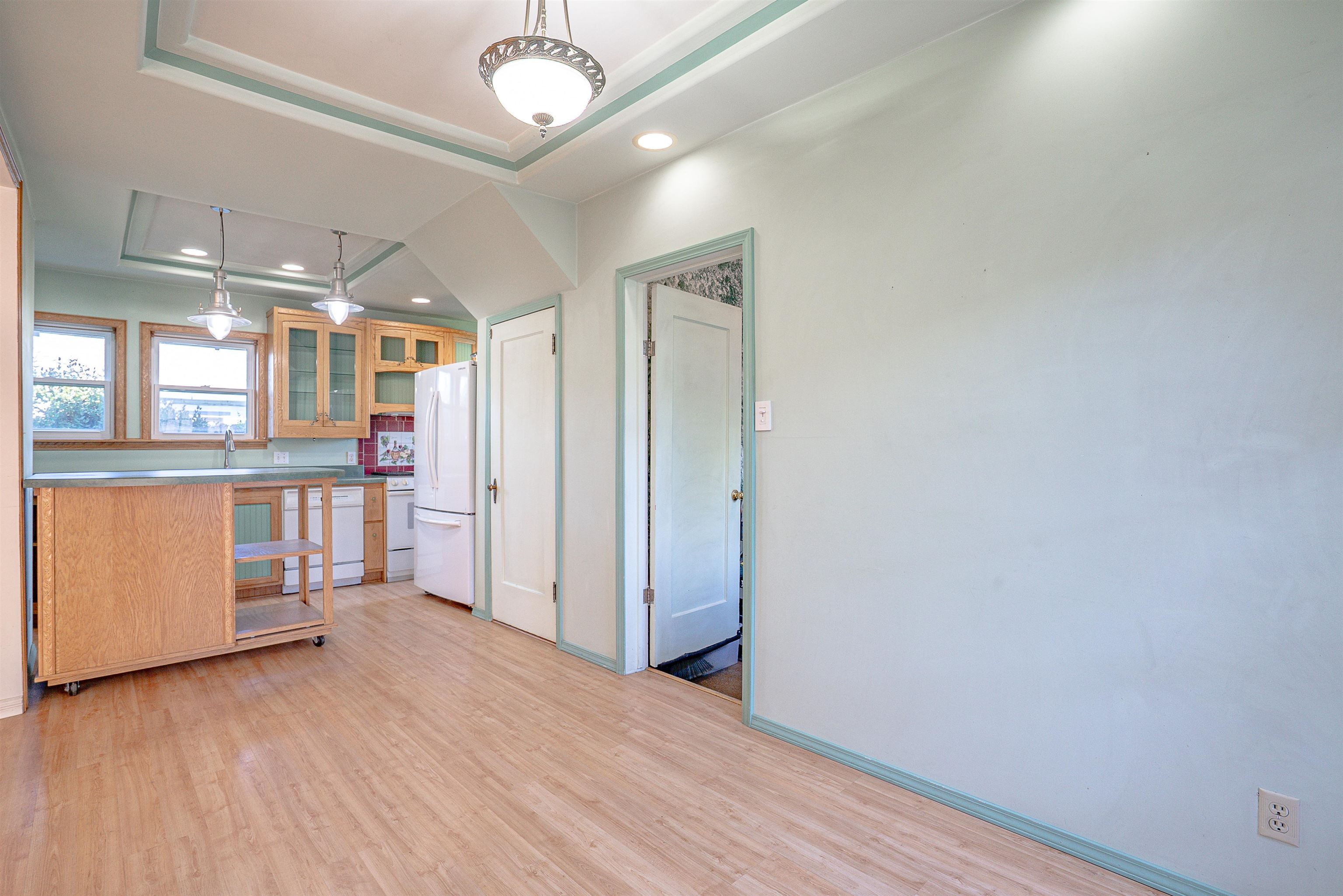 Kitchen and open dining area with wood cabinetry, mobile island, and tray ceiling.