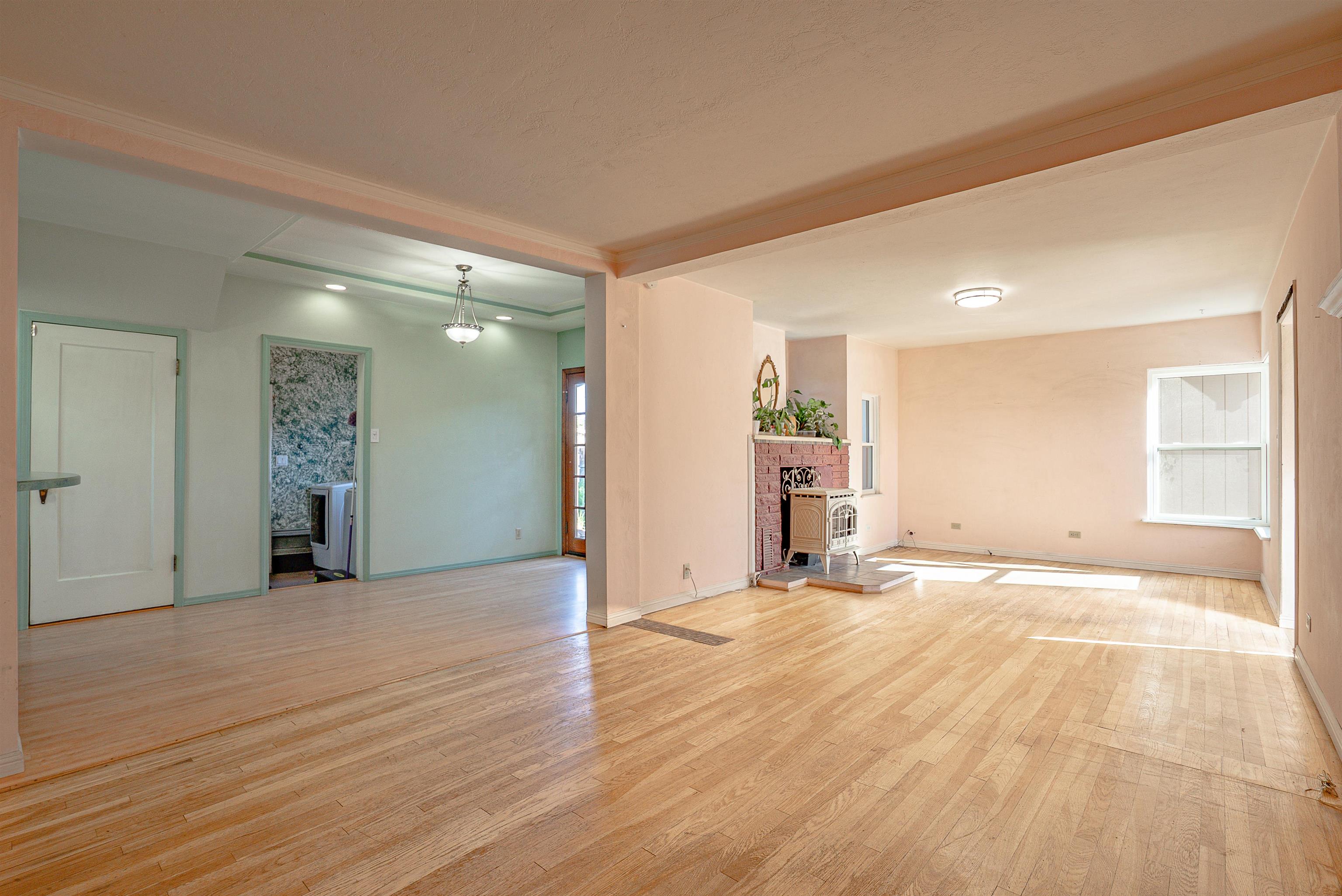 Open living room with hardwood floors, a brick fireplace and stove, and a sunny window.