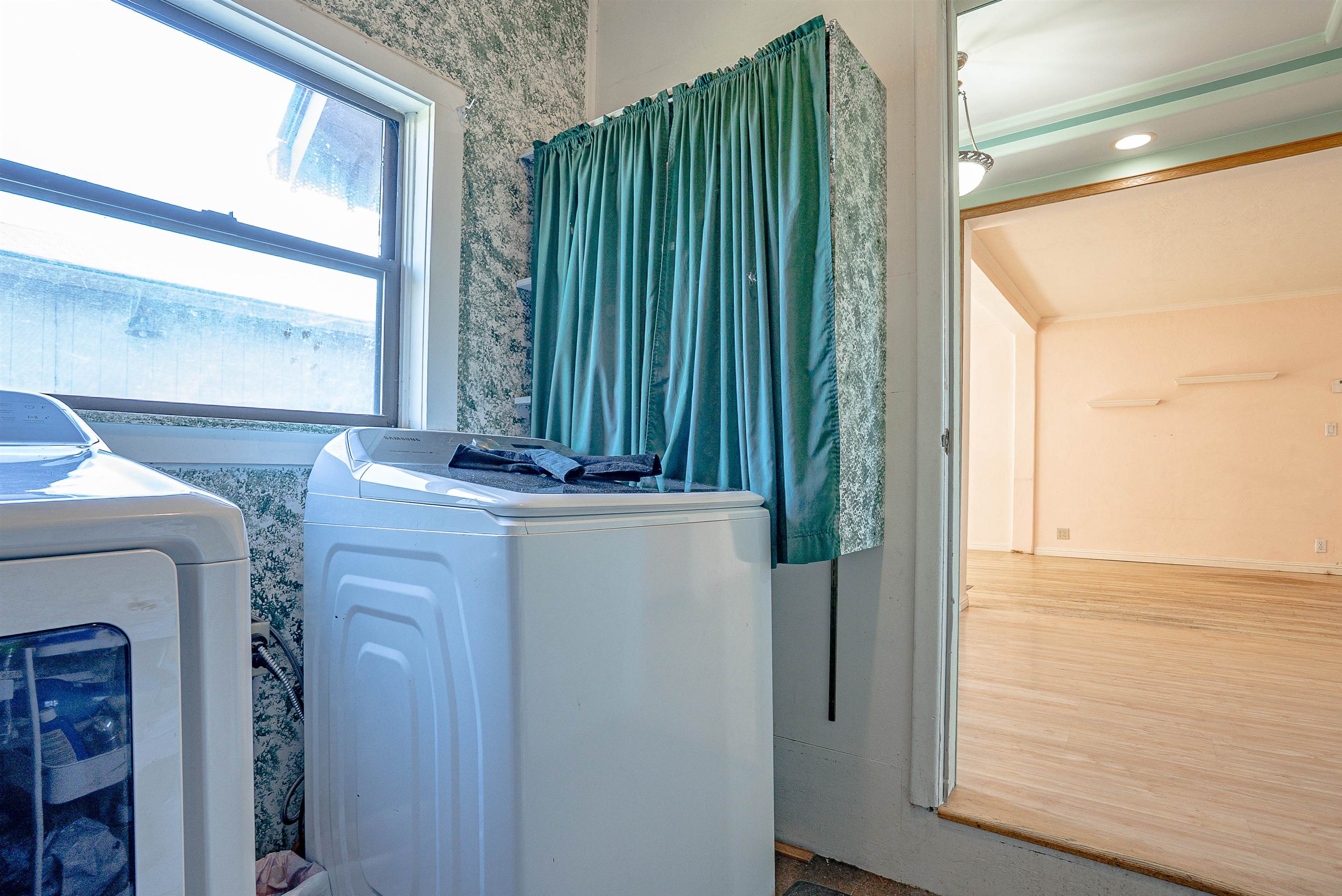 Laundry room with washer and dryer beside a doorway to an empty room.