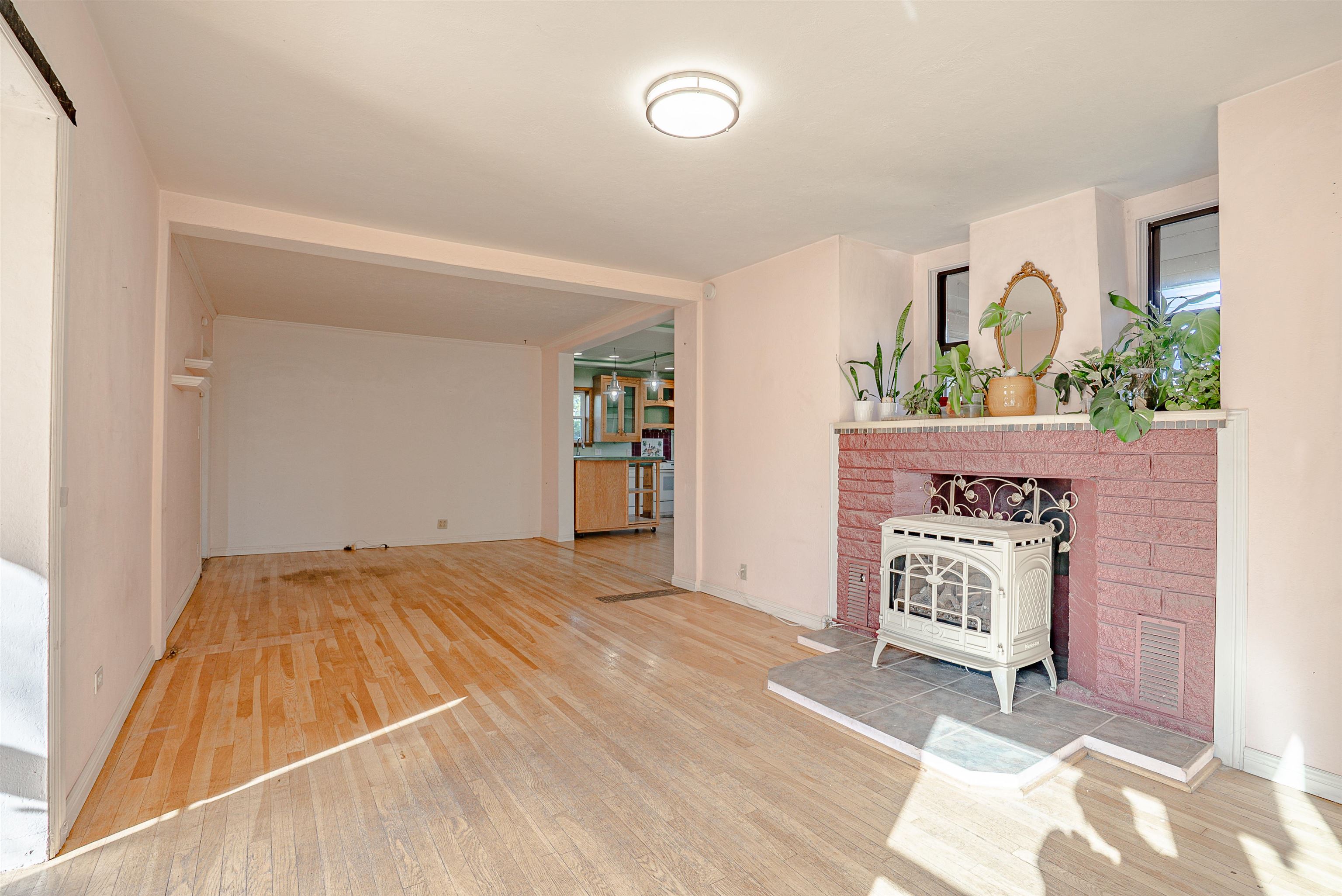 Living room with hardwood floors, a pink brick fireplace, and a white freestanding stove.