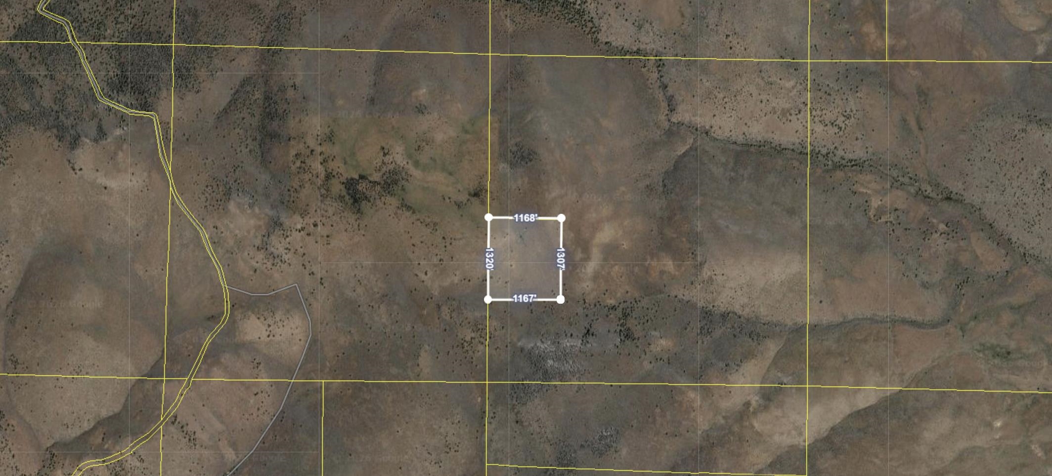Aerial view of undeveloped land with sparse vegetation and a rectangular measurement overlay.