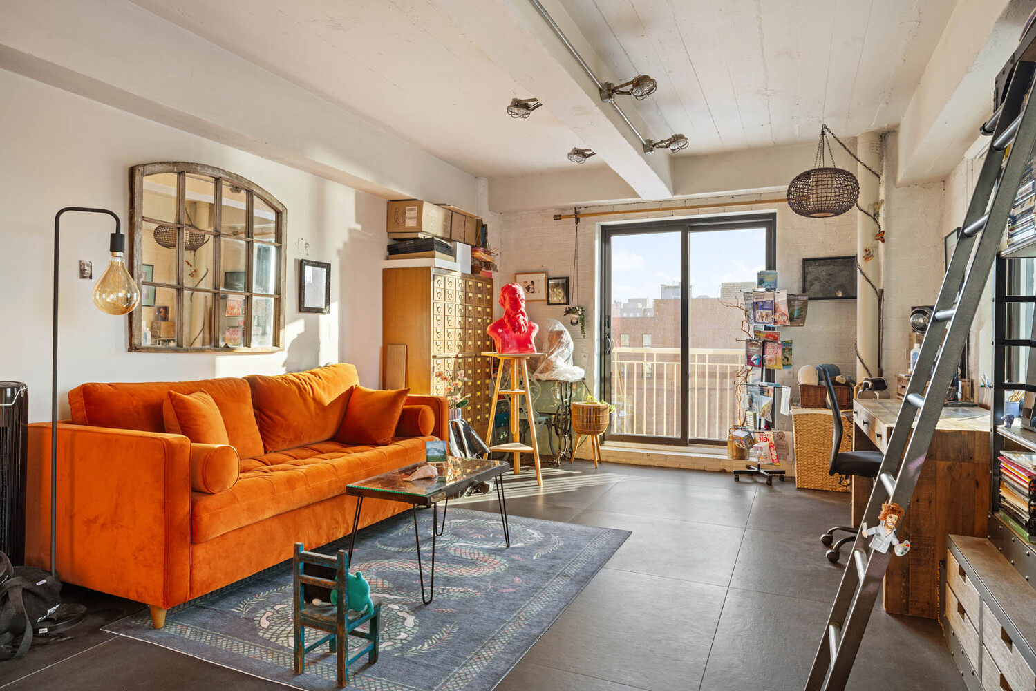 Loft living room with an orange sofa, exposed ceiling beams, and sliding doors to a balcony.