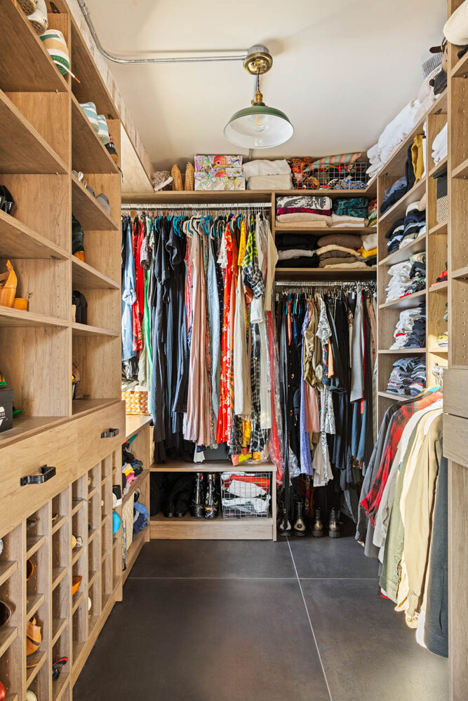 Walk-in closet with extensive wood shelving, hanging clothes, and shoe cubbies.