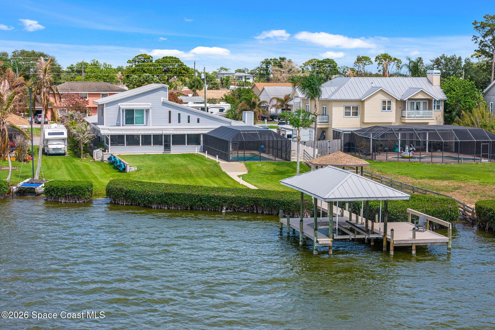 Waterfront homes along a canal, with screened pool enclosures and a covered dock.