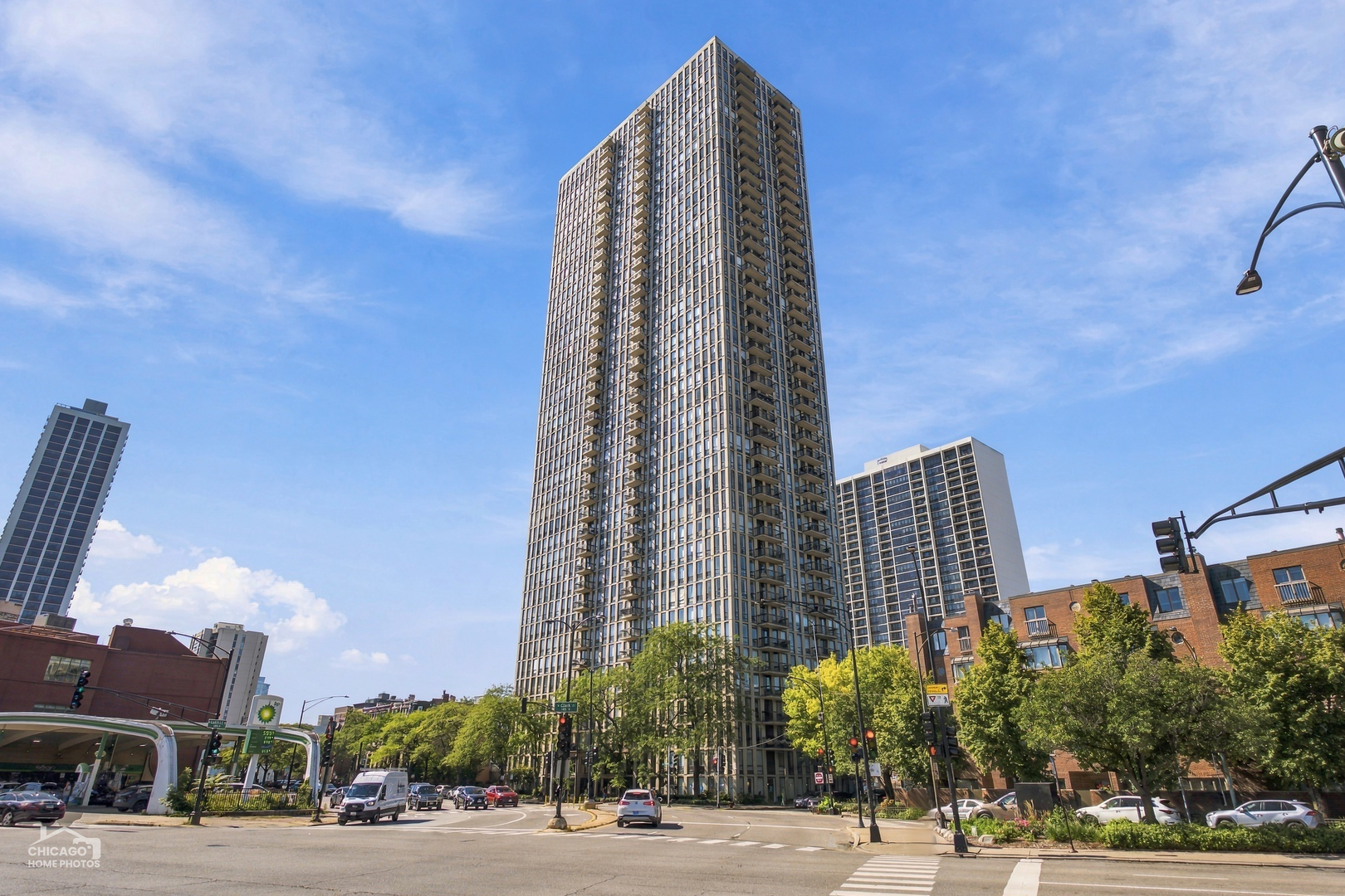 Residential high-rise with balconies rising above a tree-lined Chicago street.