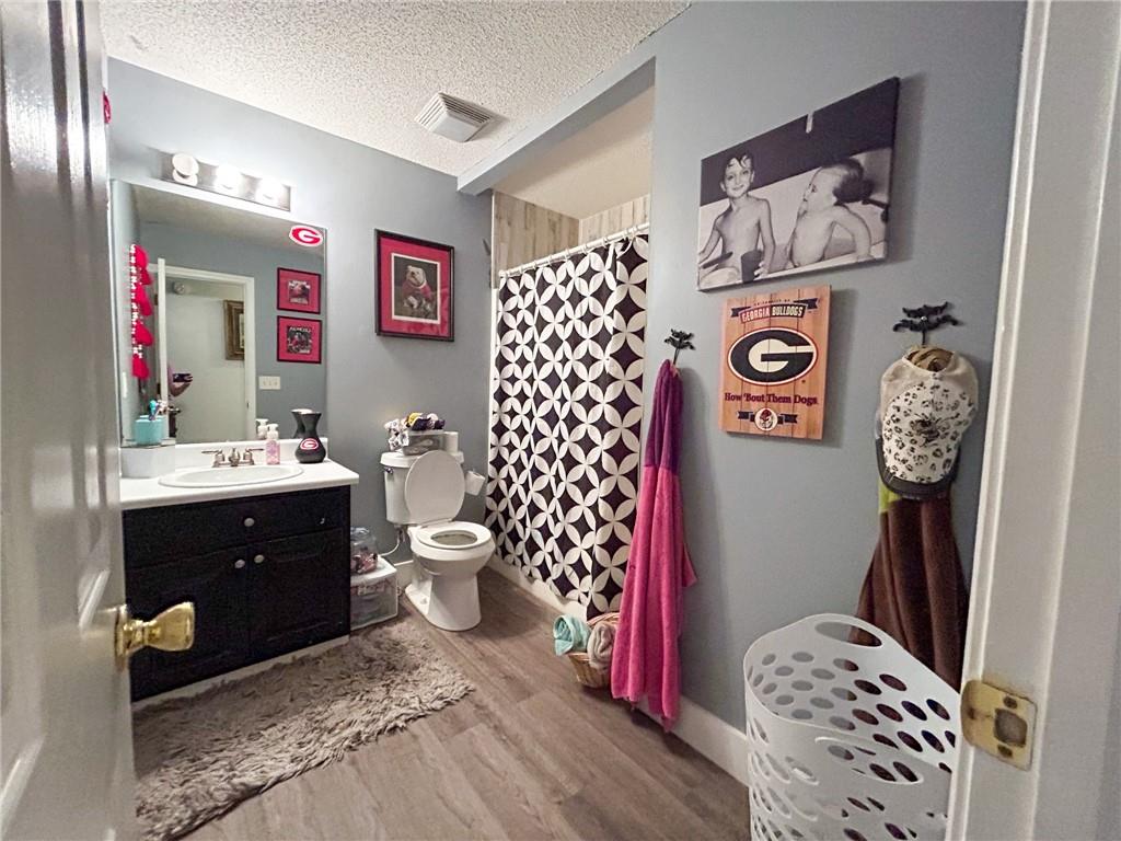 Bathroom with a dark vanity, patterned shower curtain, and Georgia Bulldogs decorations.