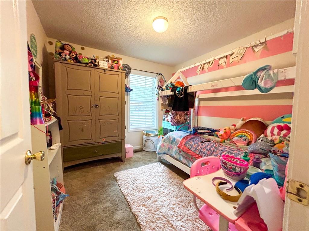 Child’s bedroom with a pink-and-white striped wall, wooden wardrobe, toys, and a bed.