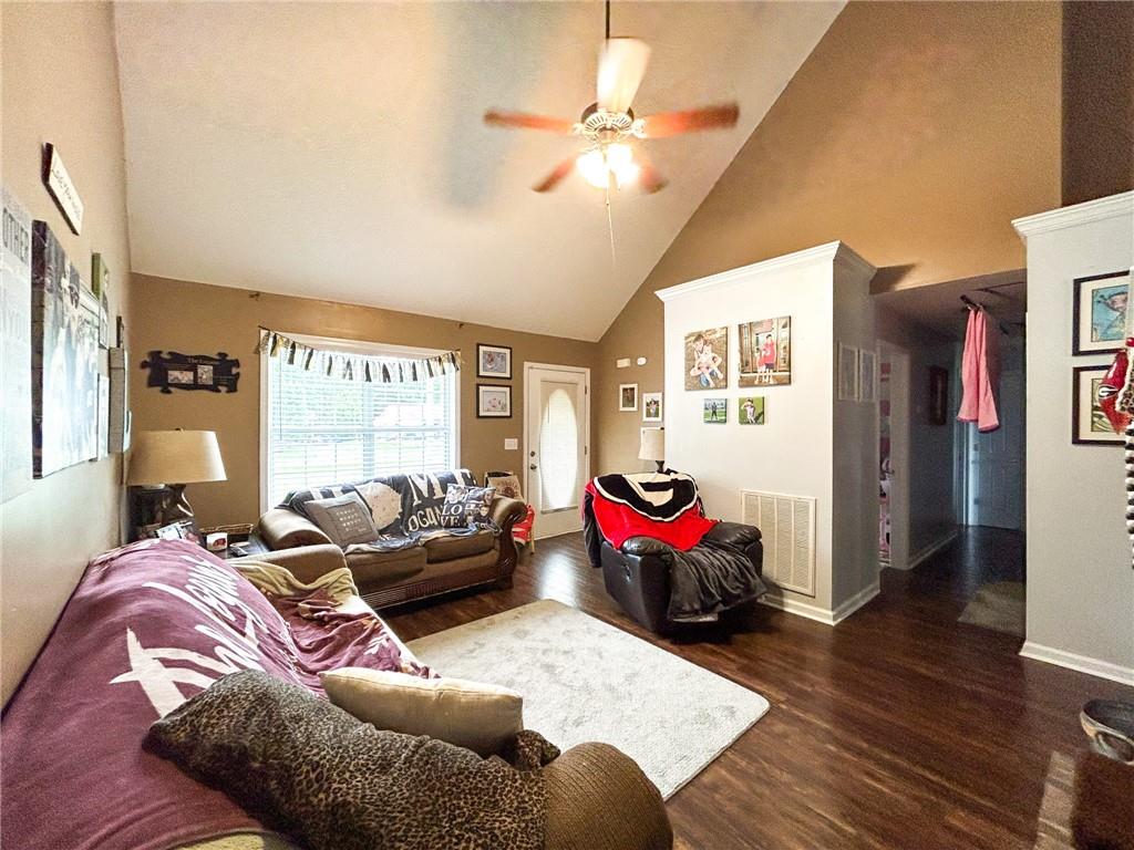 Living room with vaulted ceiling, brown leather seating, and a large window.