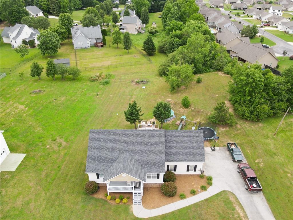 Aerial view of a single-story home with a broad grassy yard, front porch, and driveway.