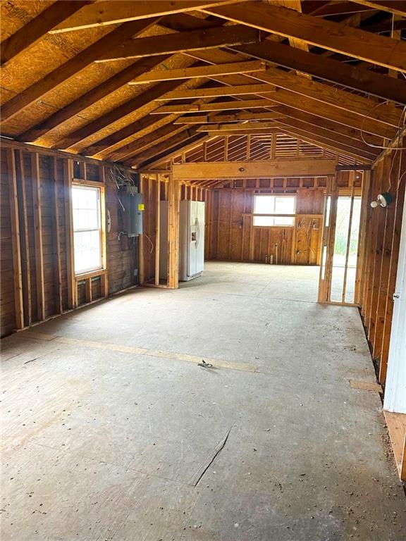 Unfinished wood-framed outbuilding with exposed roof trusses and a concrete floor.