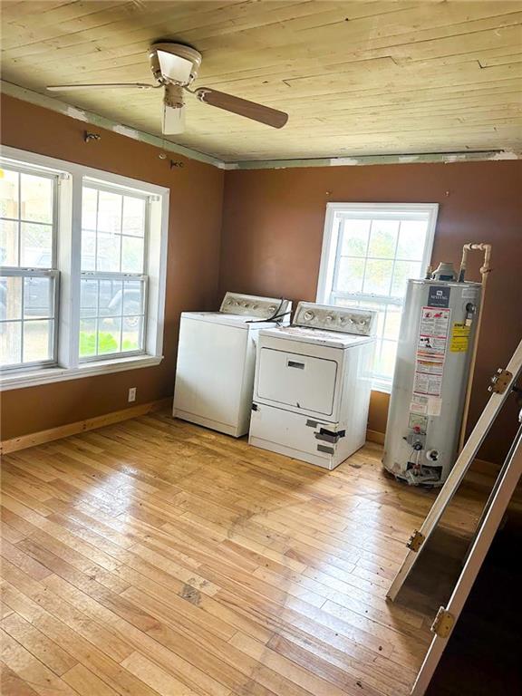 Laundry room with washer, dryer, and tall water heater beside large windows.