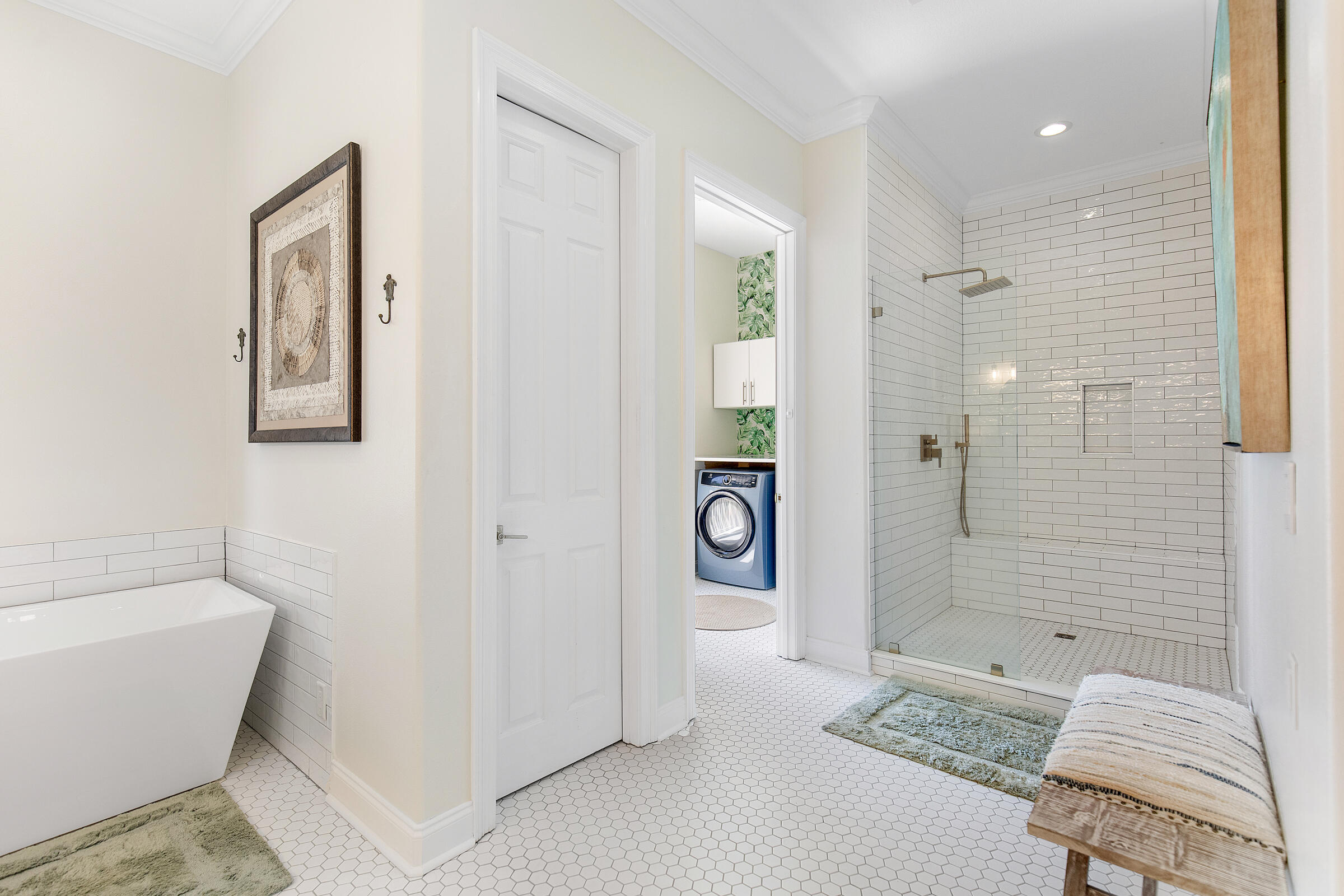 Bathroom with a freestanding tub, glass shower, and laundry closet with a front-loading washer.
