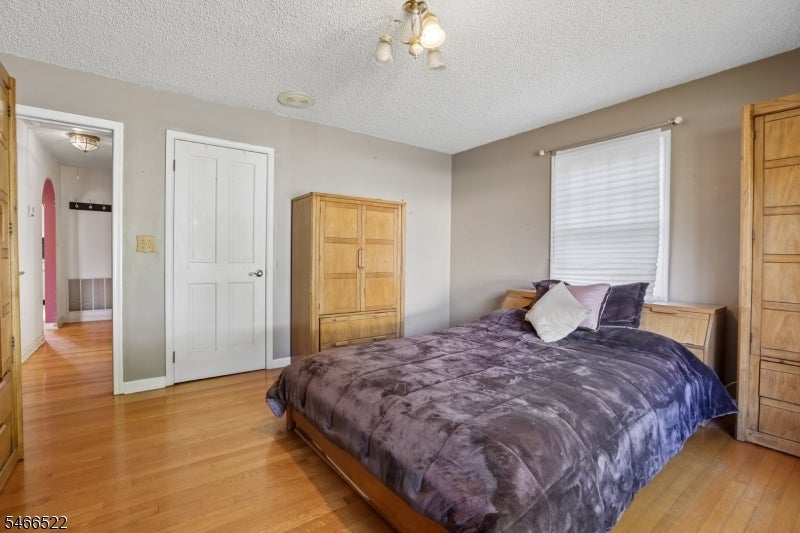 Bedroom with hardwood floors, dark purple bedding, and wooden wardrobes.