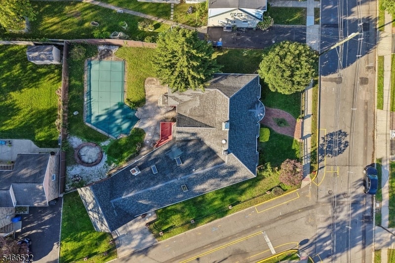 Aerial view of a house with a fenced pool and landscaped yard beside a street.